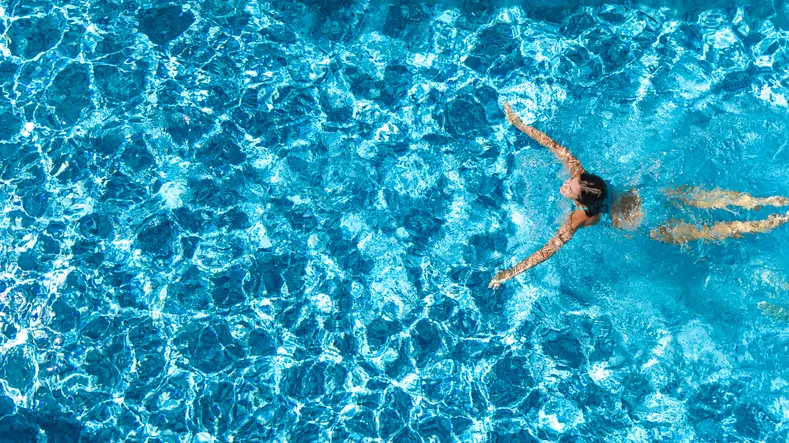 Schwimmerin von oben in türkisblauem Wasser