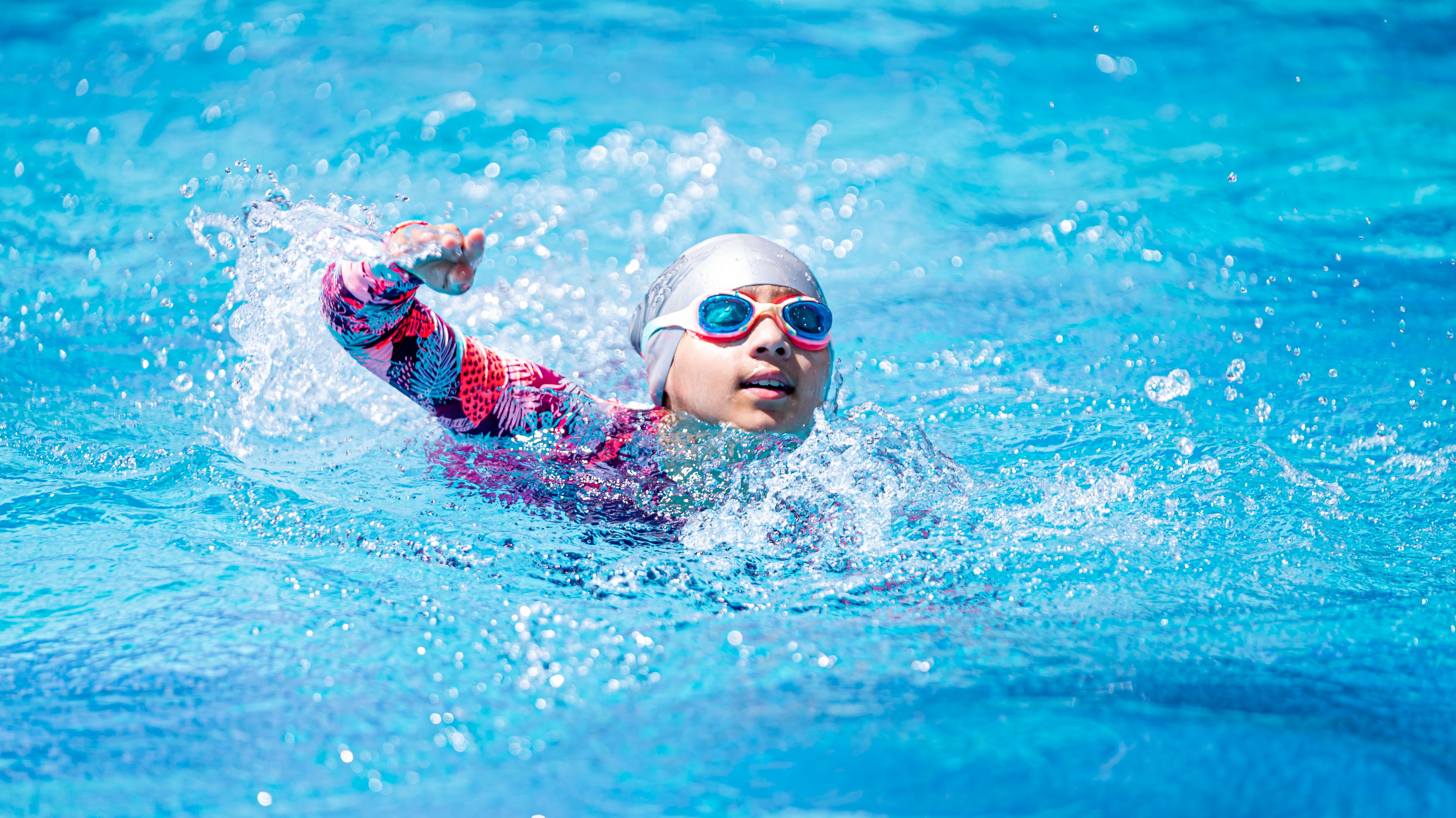 Kind schwimmt mit Schutzbrille